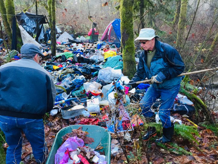 Volunteers work together to pick up piles of garbage along Piercy Creek